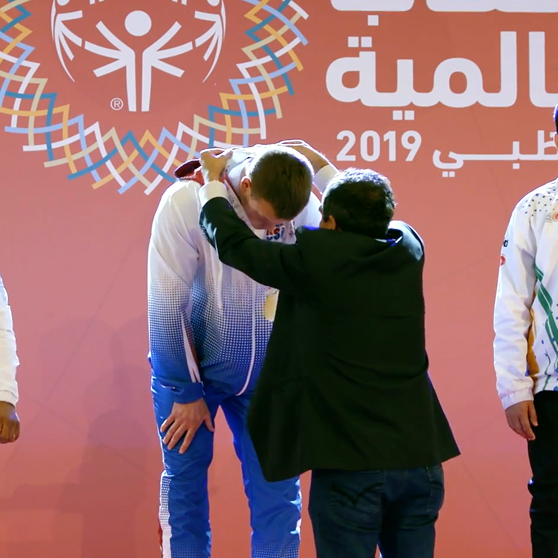 Man putting an olympic medal on an athlete